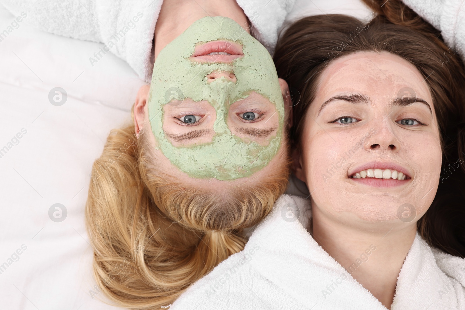 Photo of Spa day. Beautiful woman with face masks on bed, above view