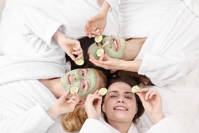 Photo of Spa day. Beautiful woman with face masks and cucumber slices on bed, above view