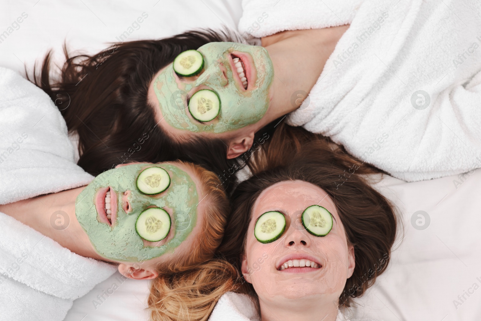 Photo of Spa day. Beautiful woman with face masks and cucumber slices on bed, above view