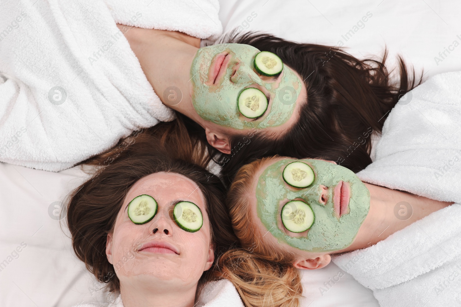 Photo of Spa day. Beautiful woman with face masks and cucumber slices on bed, above view