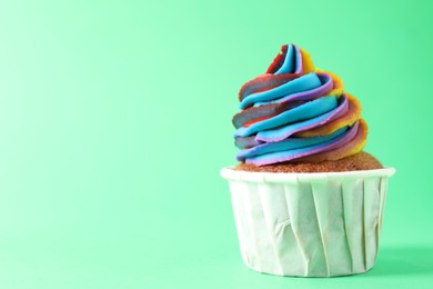 Photo of One delicious cupcake with colorful cream on green background, closeup. Space for text