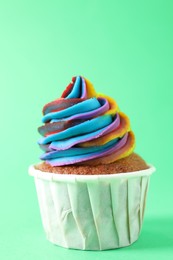 Photo of One delicious cupcake with colorful cream on green background, closeup