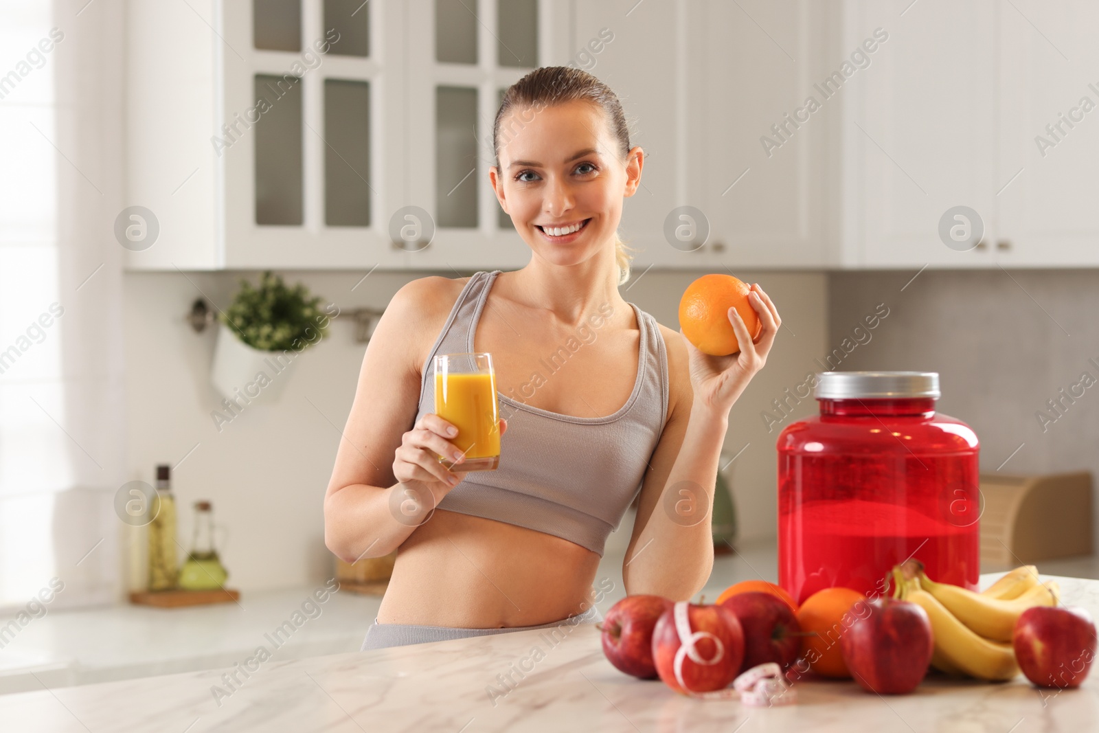 Photo of Weight loss. Happy woman with tasty shake and orange at white marble table in kitchen