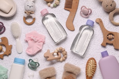 Photo of Baby oil, socks and accessories on white towel, top view