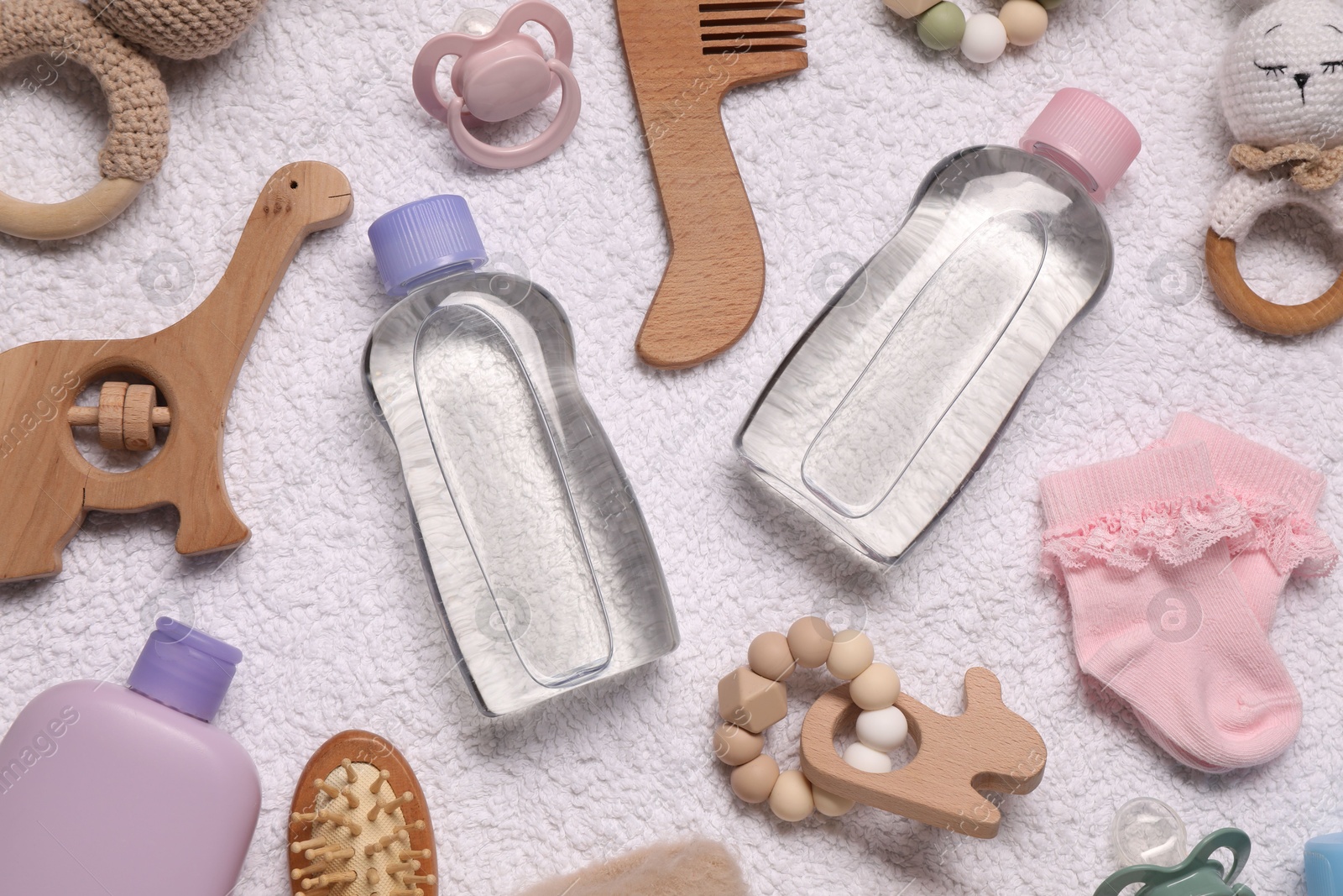 Photo of Baby oil, socks and accessories on white towel, top view