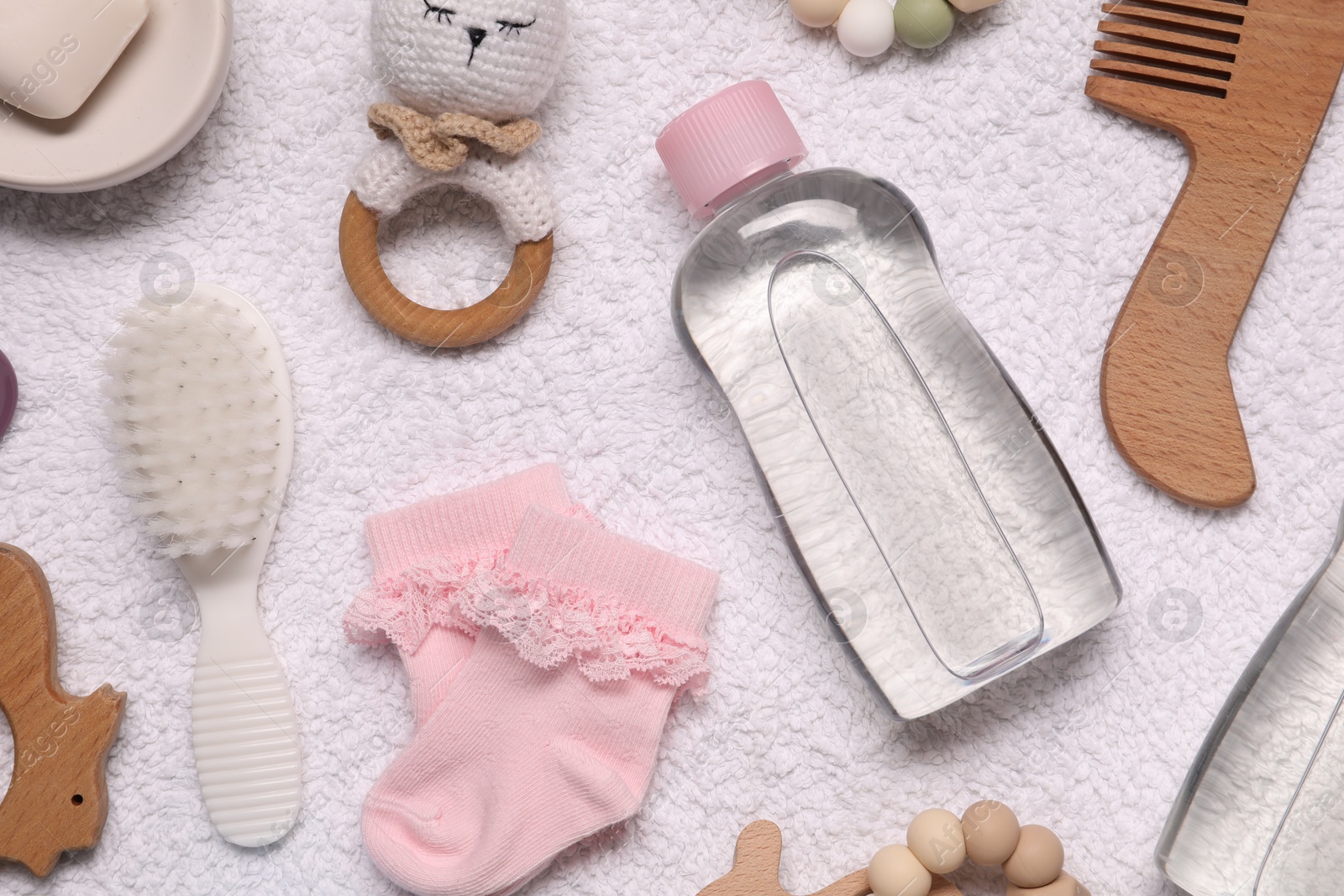 Photo of Baby oil, socks and accessories on white towel, top view