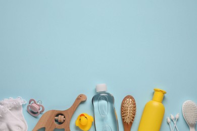 Photo of Baby oil and bath accessories on light blue background, flat lay. Space for text