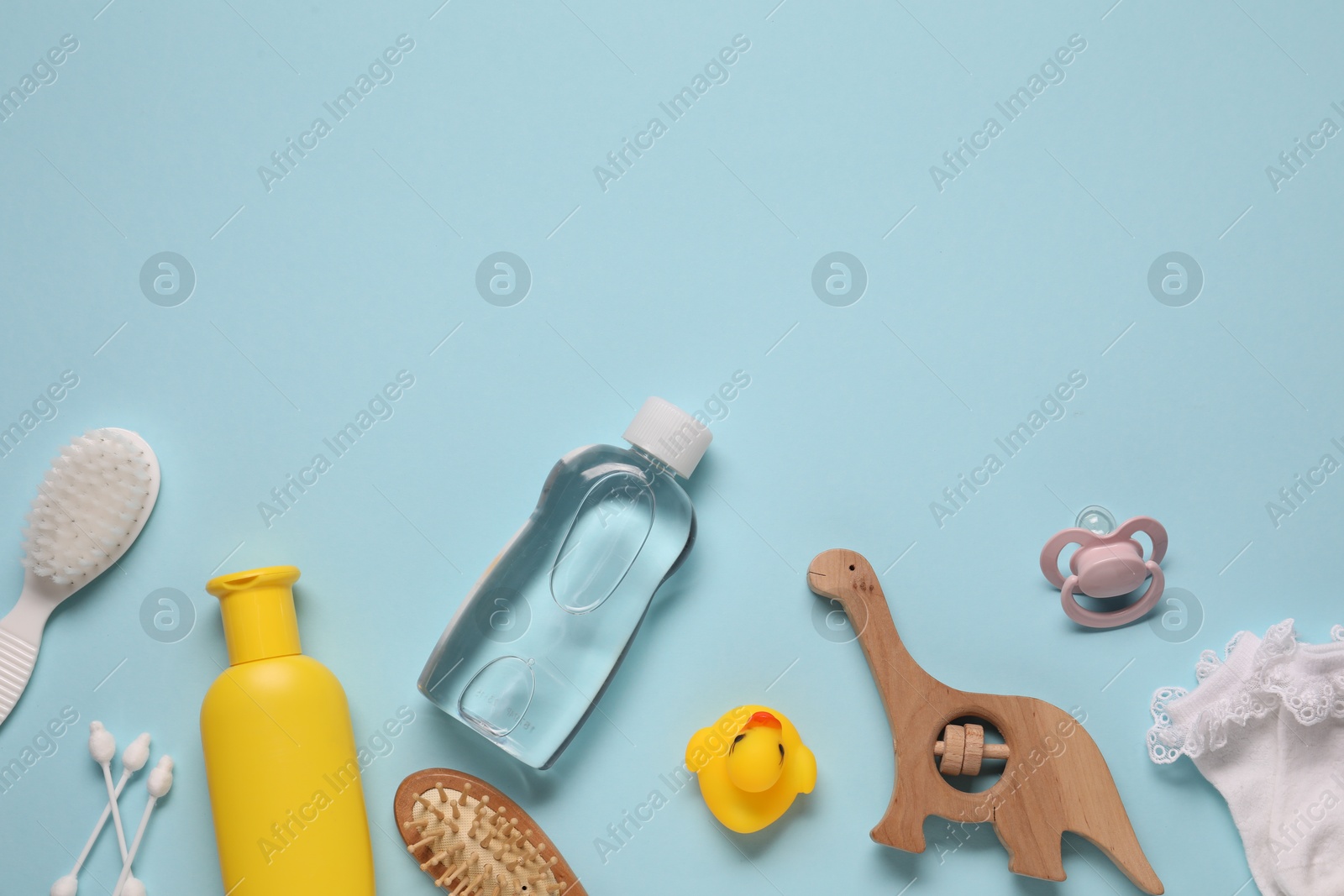 Photo of Baby oil and bath accessories on light blue background, flat lay. Space for text