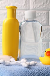 Photo of Baby care products and bath accessories on blue towel against white brick wall, closeup