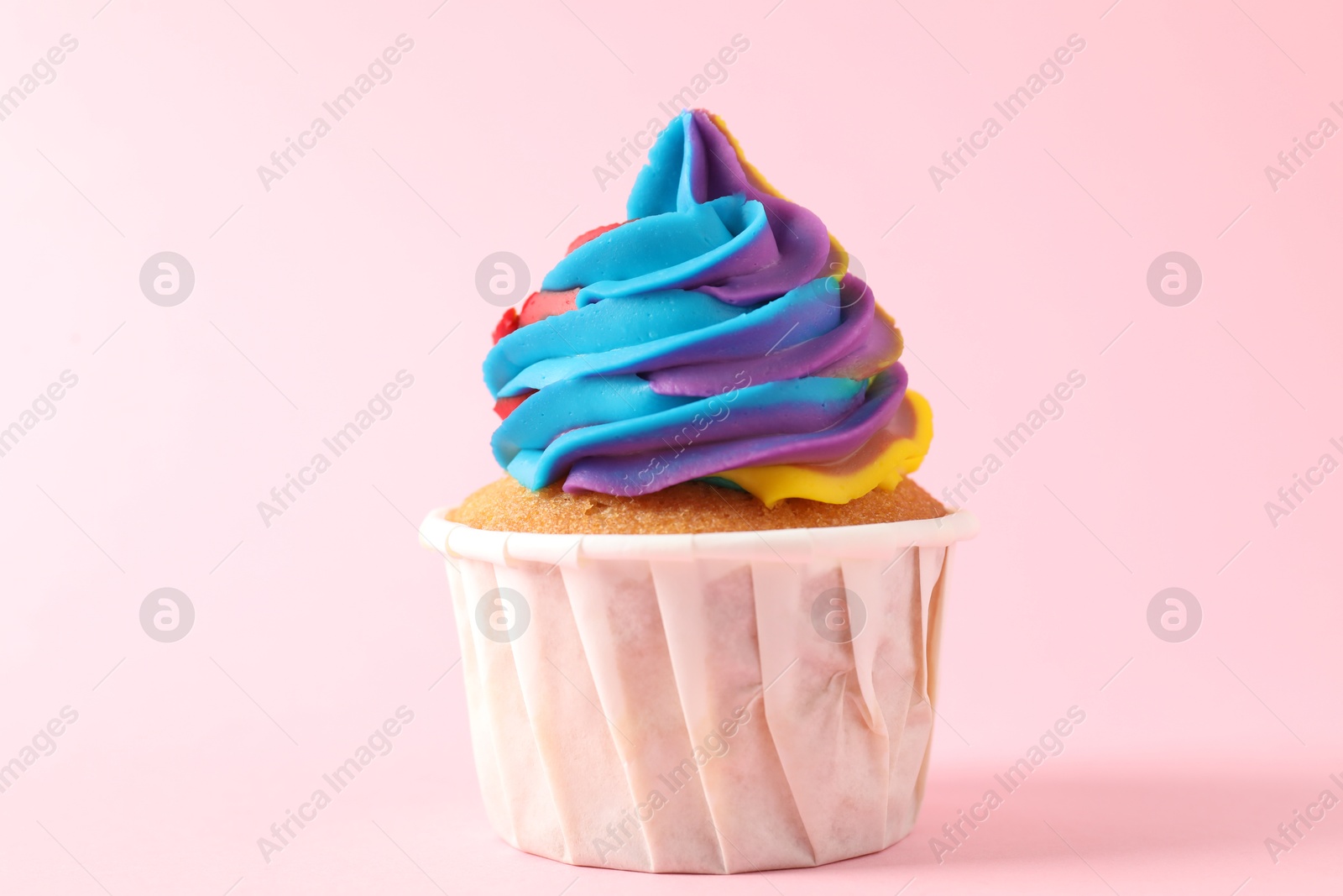 Photo of One delicious cupcake with colorful cream on pink background, closeup