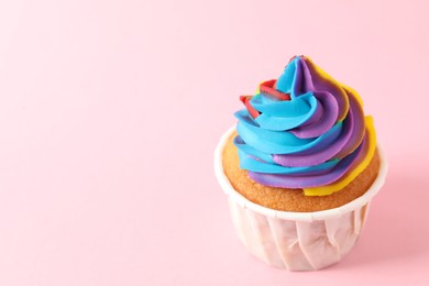 Photo of One delicious cupcake with colorful cream on pink background, closeup. Space for text