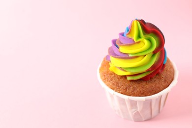 Photo of One delicious cupcake with colorful cream on pink background, closeup. Space for text