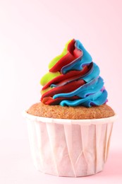 Photo of One delicious cupcake with colorful cream on pink background, closeup