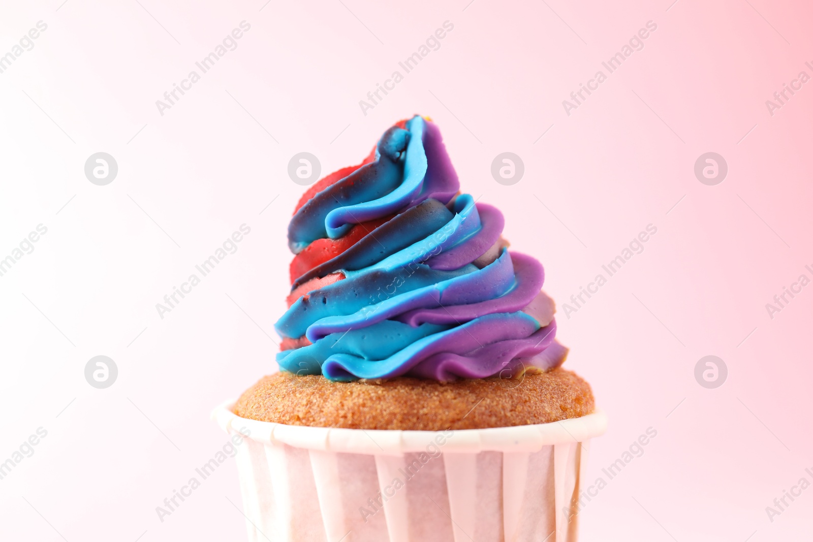 Photo of One delicious cupcake with colorful cream on pink background, closeup