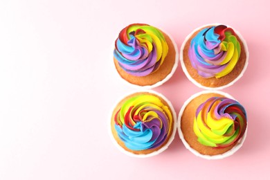 Photo of Delicious cupcakes with colorful cream on pink background, flat lay. Space for text