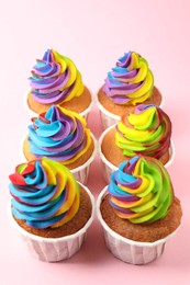 Photo of Delicious cupcakes with colorful cream on pink background, closeup