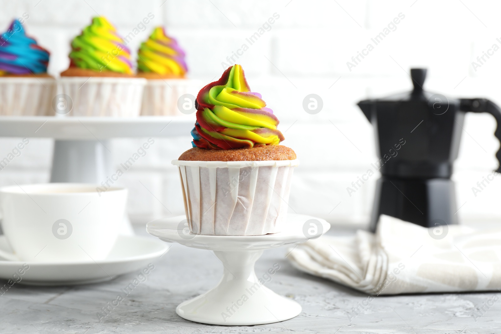 Photo of Delicious cupcake with colorful cream on grey textured table, closeup