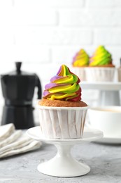 Photo of Delicious cupcake with colorful cream on grey textured table, closeup