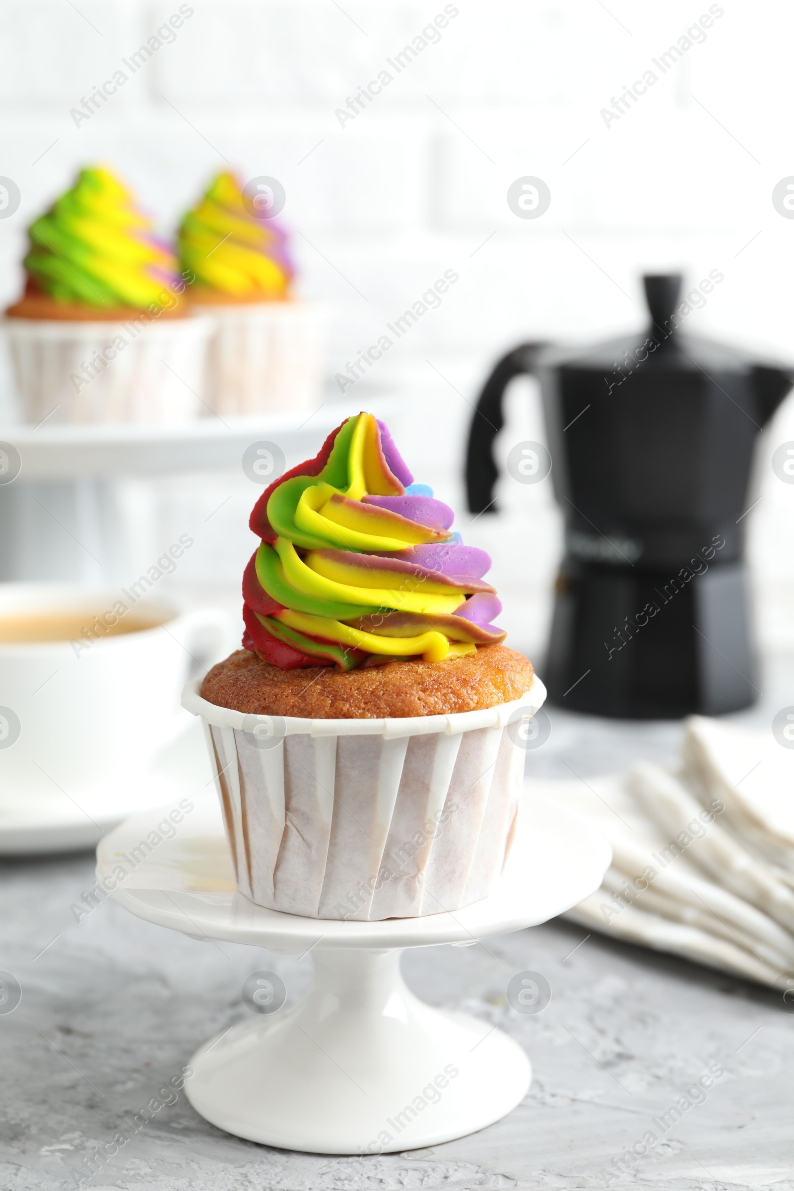 Photo of Delicious cupcake with colorful cream on grey textured table, closeup