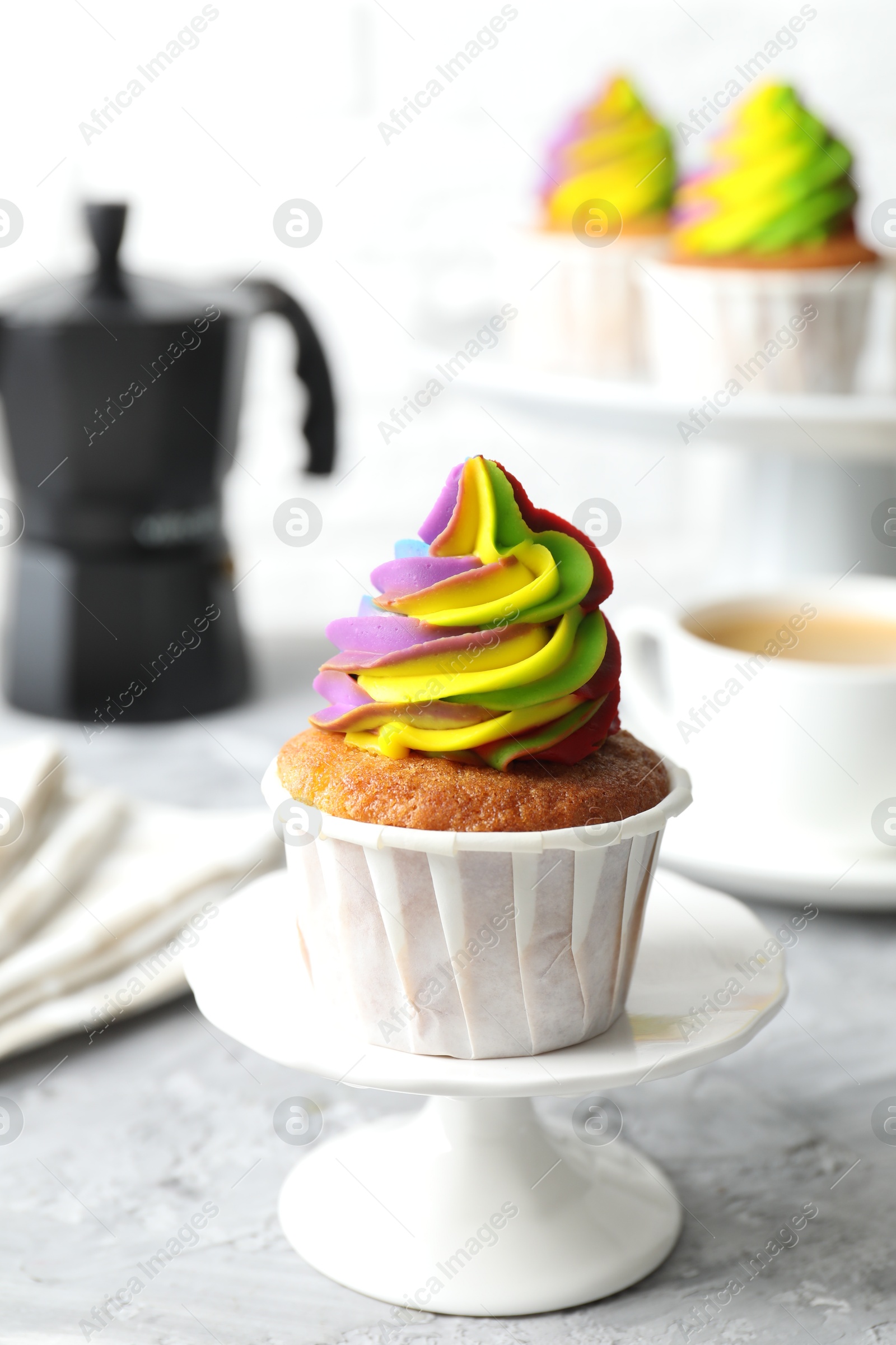 Photo of Delicious cupcake with colorful cream on grey textured table, closeup