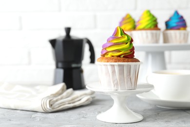 Photo of Delicious cupcake with colorful cream on grey textured table, closeup. Space for text