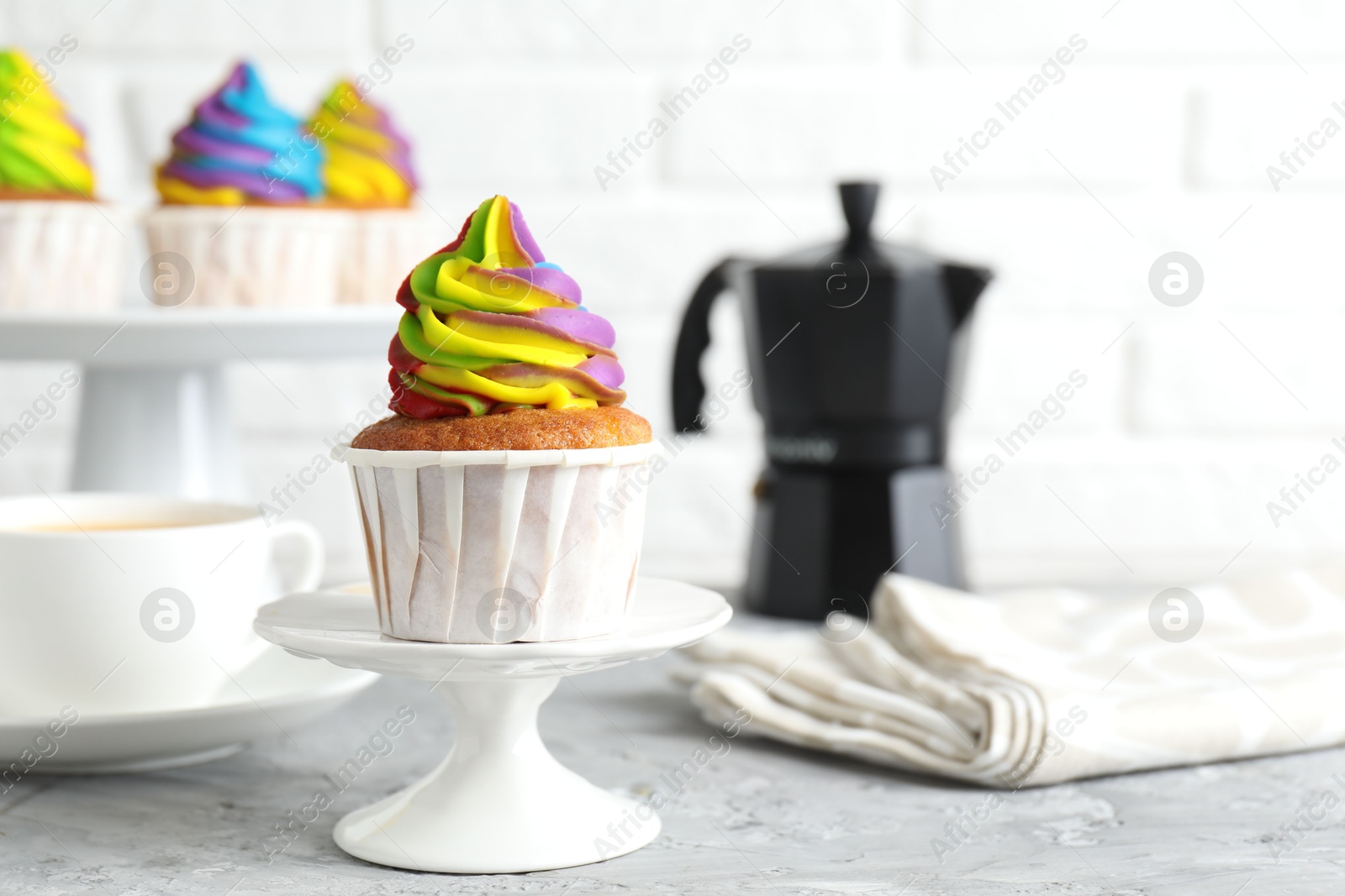 Photo of Delicious cupcake with colorful cream on grey textured table, closeup. Space for text