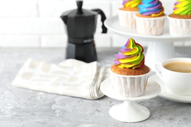 Photo of Delicious cupcake with colorful cream on grey textured table, closeup. Space for text