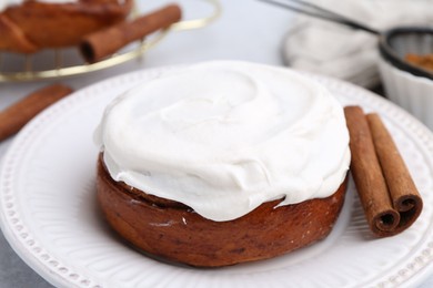 Photo of Tasty cinnamon roll with cream and spices on table, closeup