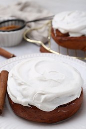 Photo of Tasty cinnamon rolls with cream and spices on table, closeup