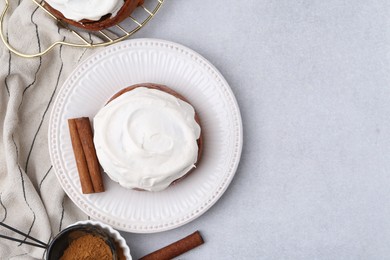 Photo of Tasty cinnamon roll with cream and spices on light table, flat lay. Space for text