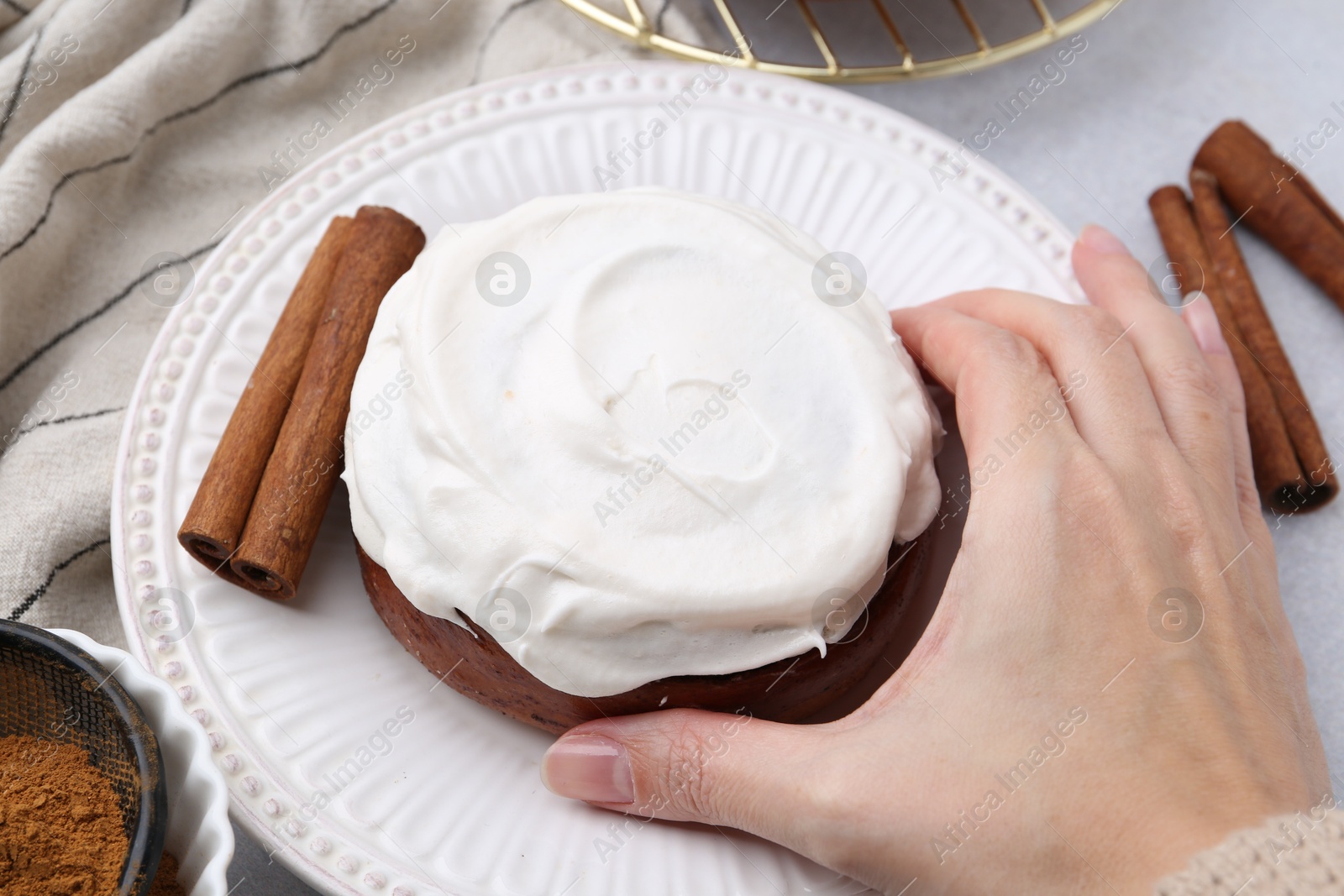 Photo of Woman tasty cinnamon roll at table, closeup