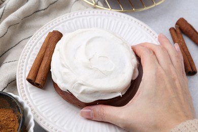 Photo of Woman tasty cinnamon roll at table, closeup