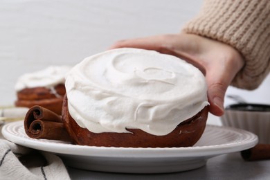 Photo of Woman tasty cinnamon roll at table, closeup