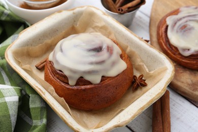 Photo of Tasty cinnamon rolls with cream and spices on white wooden table, closeup