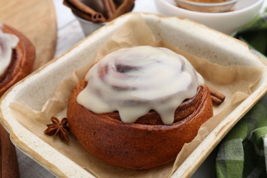 Photo of Tasty cinnamon roll with cream and spices in baking dish, closeup