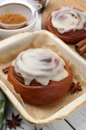 Photo of Tasty cinnamon rolls with cream and spices on white wooden table, closeup