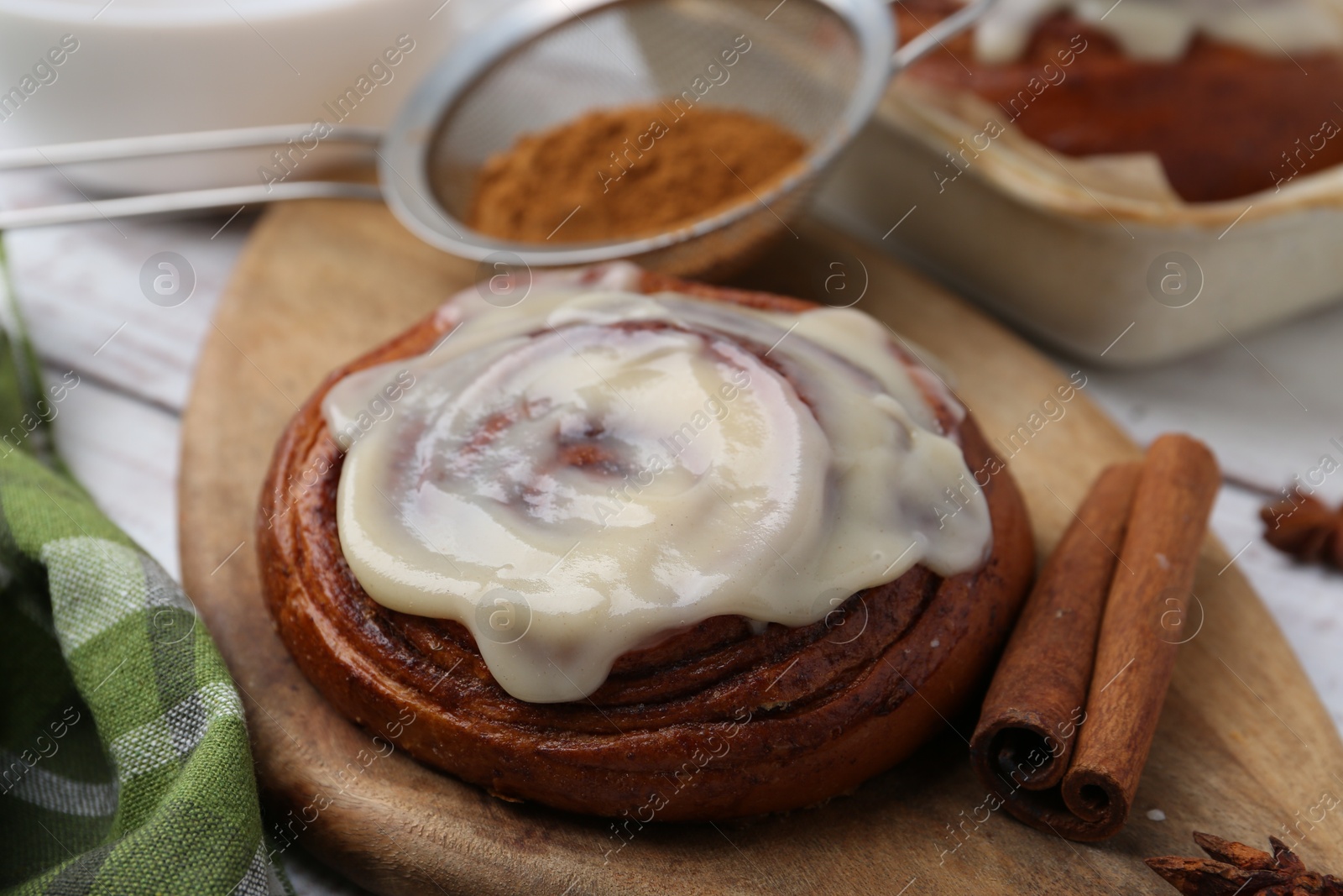 Photo of Tasty cinnamon roll with cream and spices on table, closeup