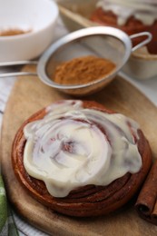 Photo of Tasty cinnamon roll with cream and spices on table, closeup