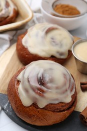 Photo of Tasty cinnamon rolls with cream on table, closeup