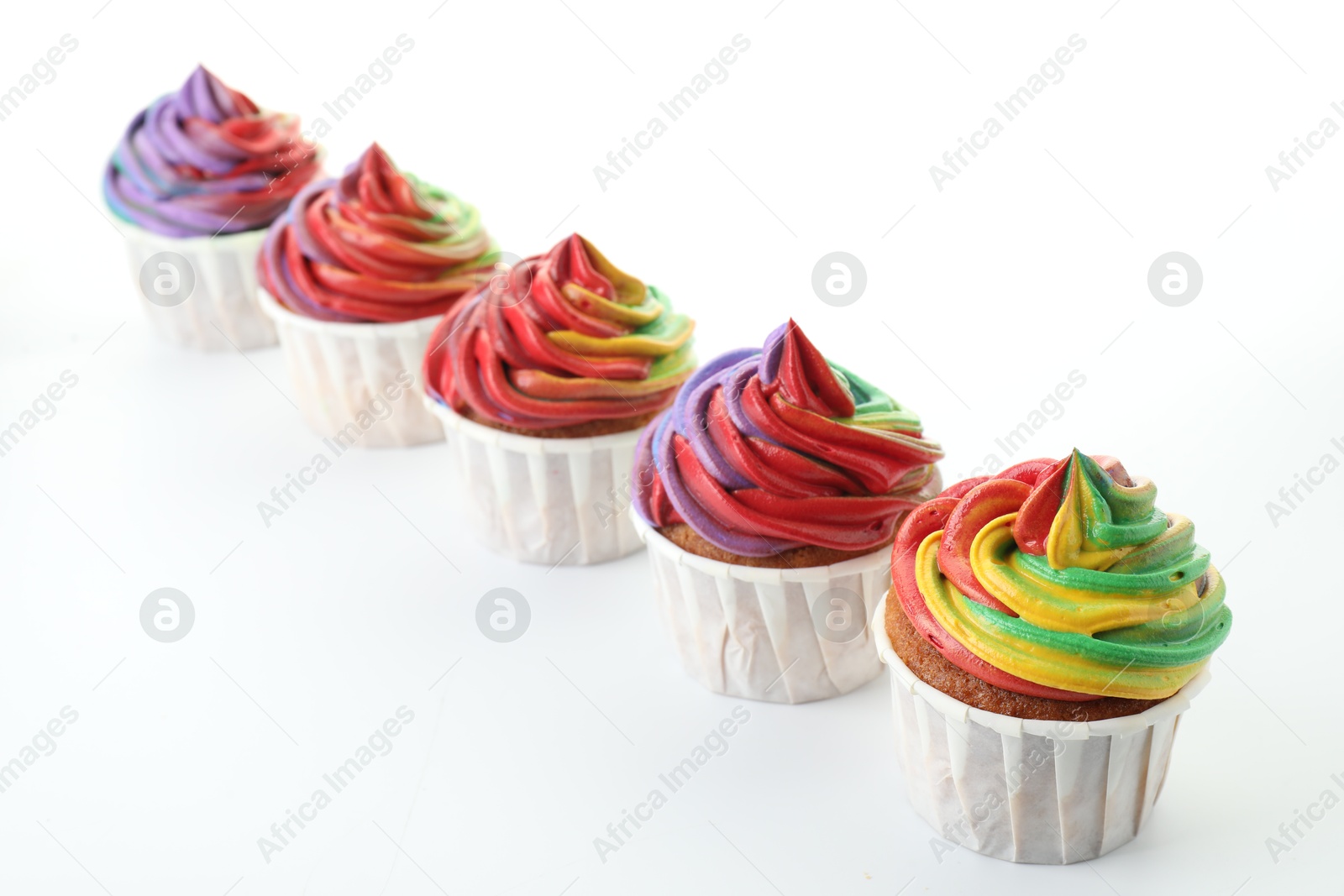 Photo of Delicious cupcakes with colorful cream on white background, closeup