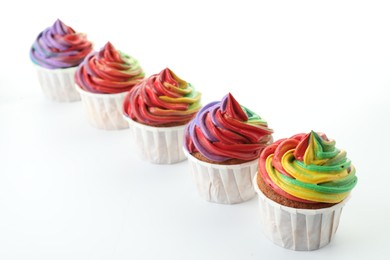 Photo of Delicious cupcakes with colorful cream on white background, closeup