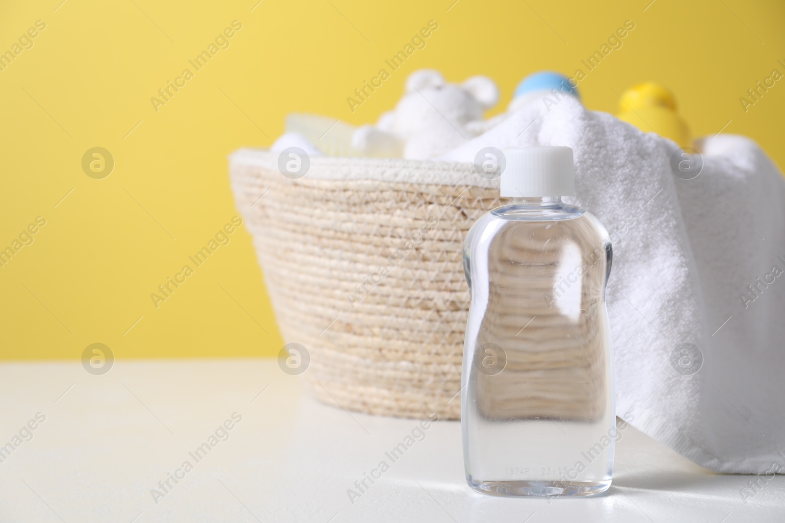 Photo of Baby oil and other toiletries on white table against yellow background. Space for text