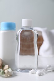 Photo of Baby oil, powder, cotton swabs and teether on white table against blurred background