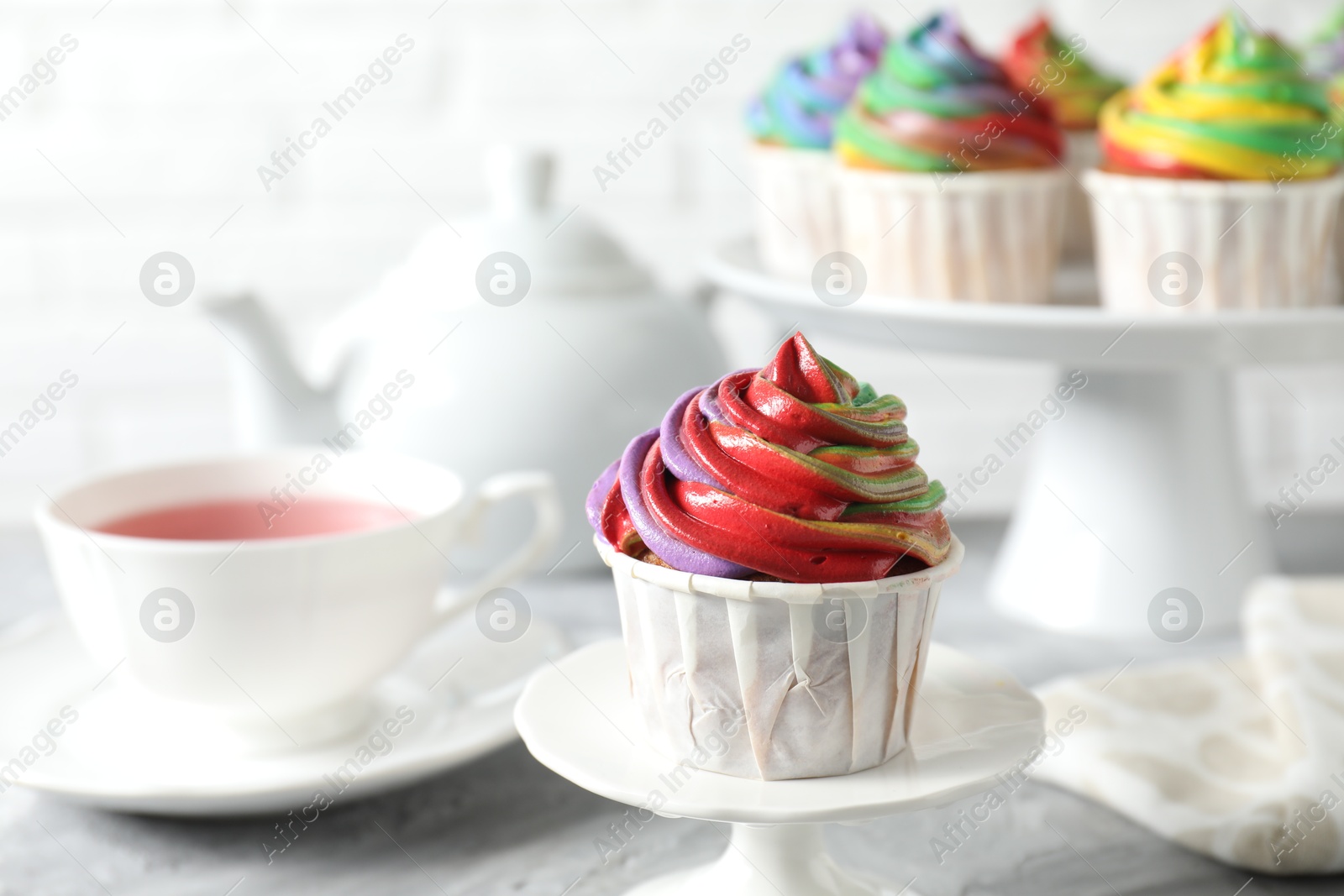 Photo of Delicious cupcake with colorful cream on grey table, closeup