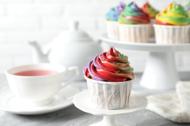 Photo of Delicious cupcake with colorful cream on grey table, closeup