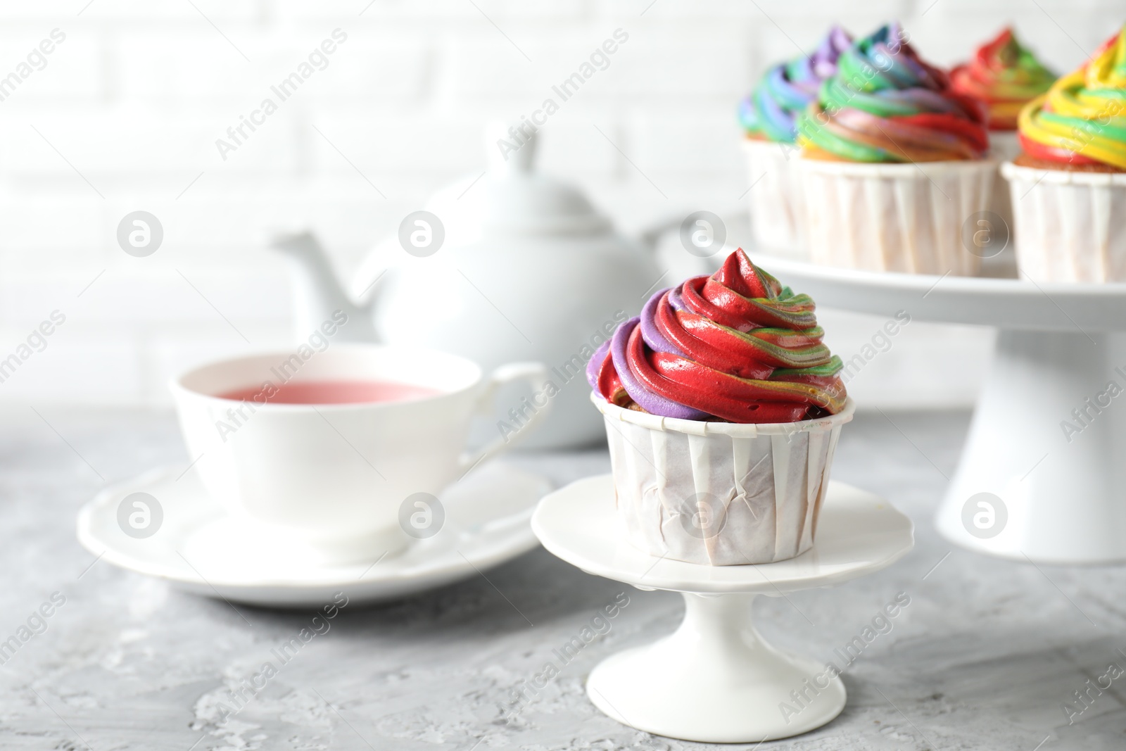 Photo of Delicious cupcake with colorful cream on grey textured table, closeup