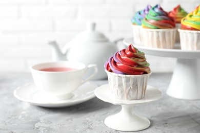 Photo of Delicious cupcake with colorful cream on grey textured table, closeup