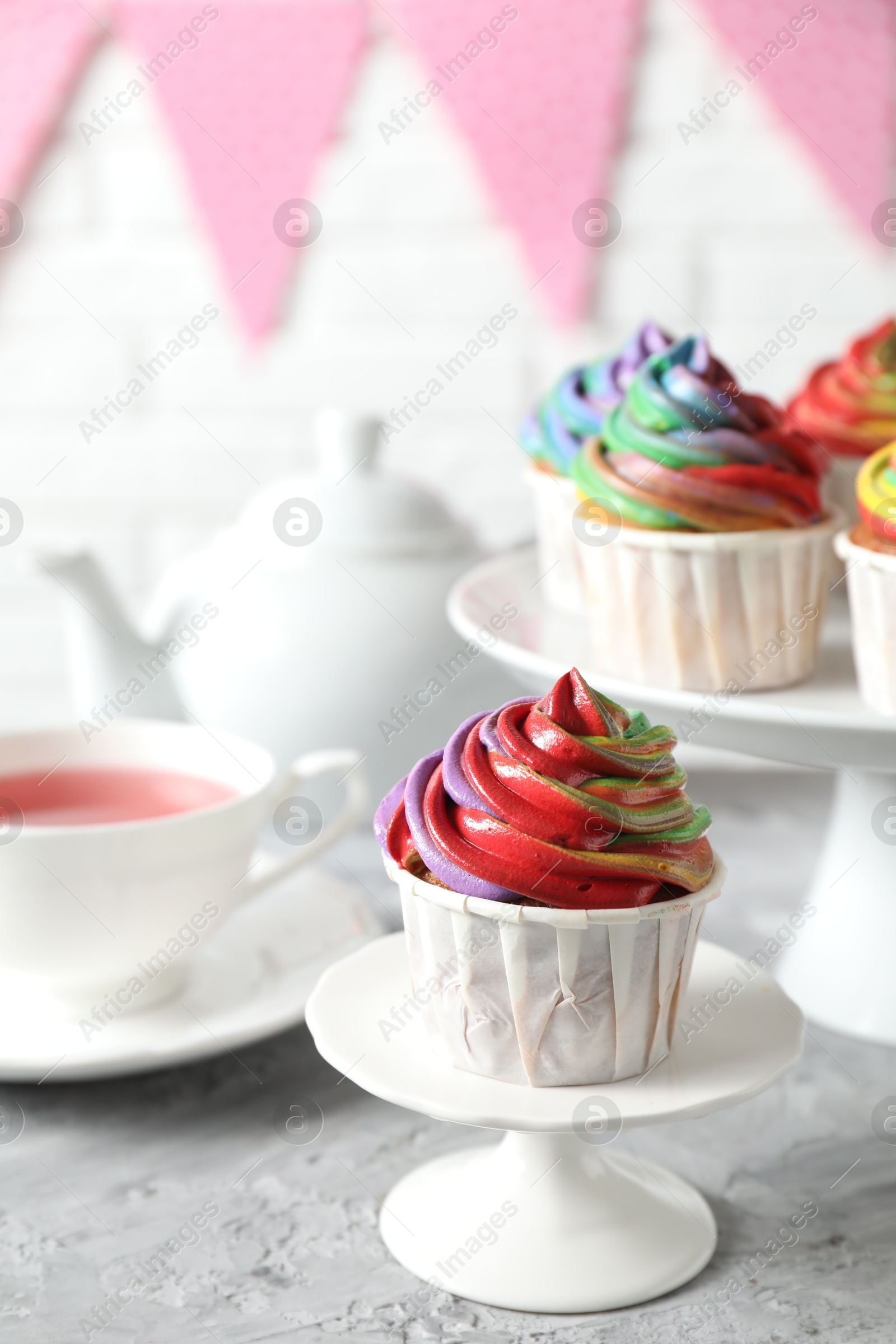 Photo of Delicious cupcake with colorful cream on grey textured table, closeup