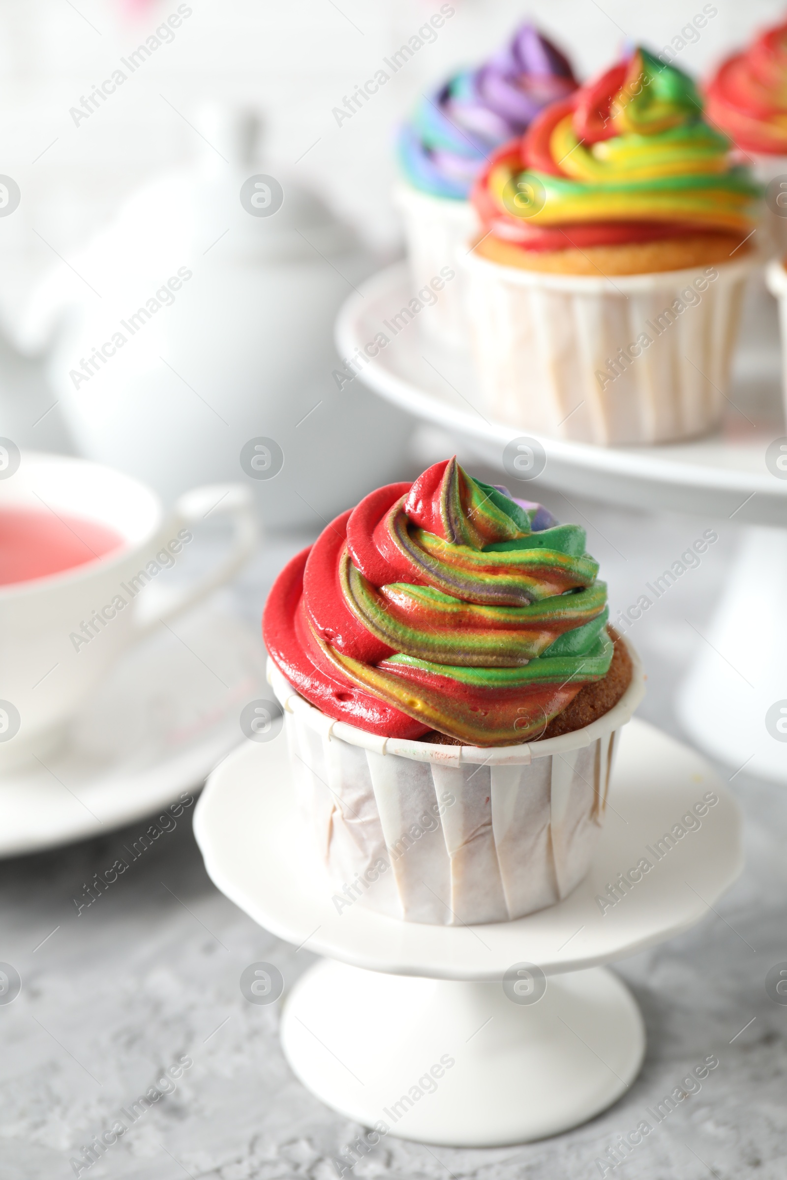 Photo of Delicious cupcake with colorful cream on grey textured table, closeup