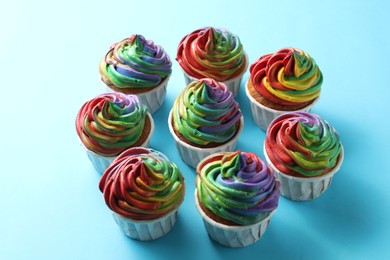 Photo of Delicious cupcakes with colorful cream on light blue background